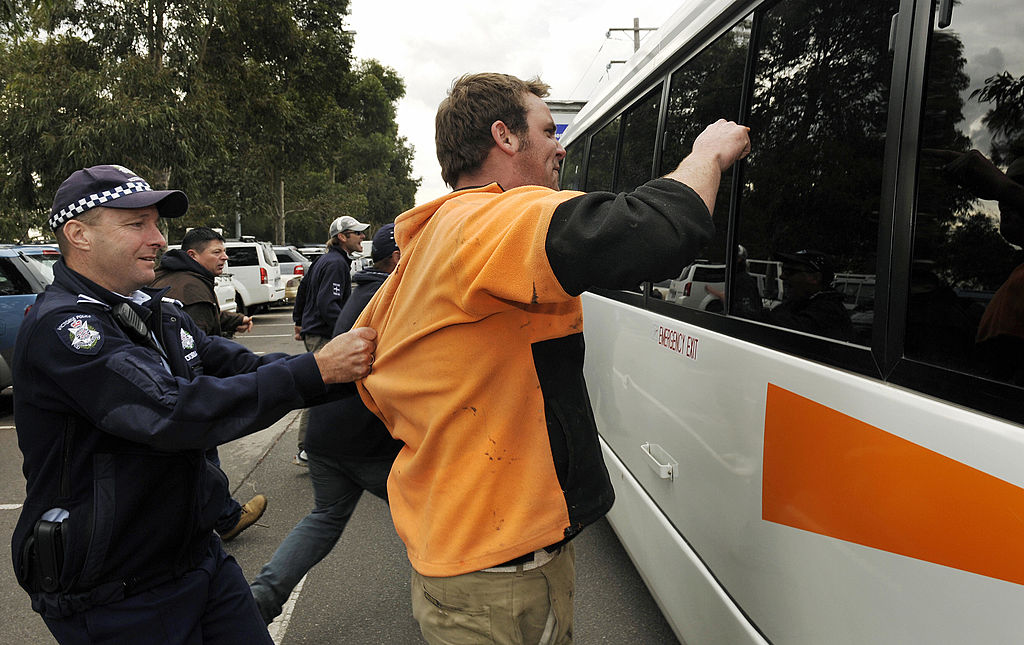 Police pull union members away from a bu